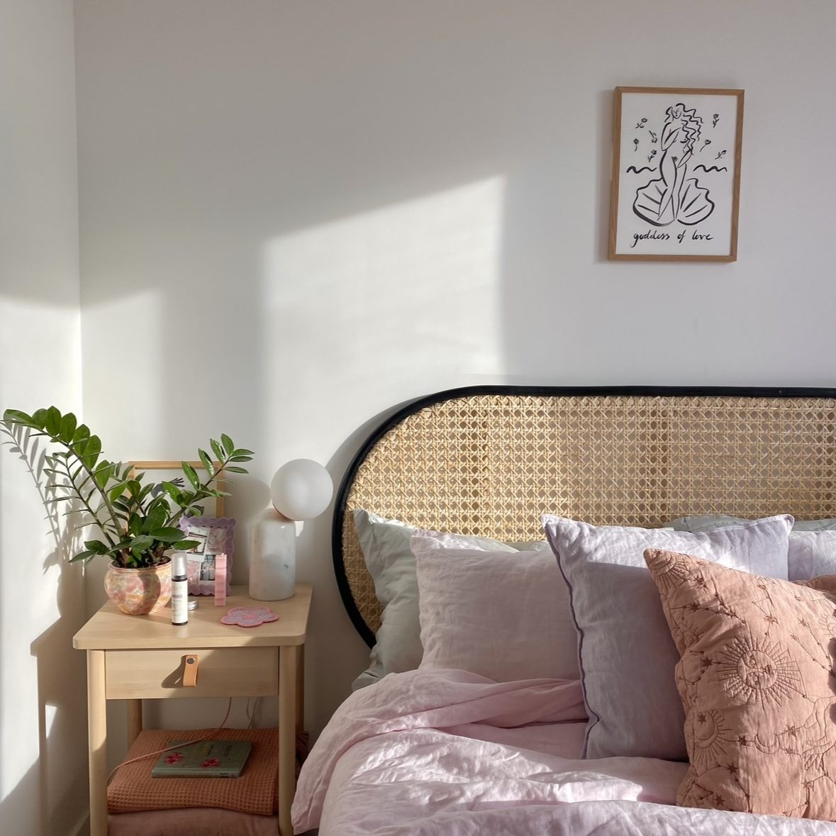 Small bedroom that features a freestanding headboard made from cane rattan.
