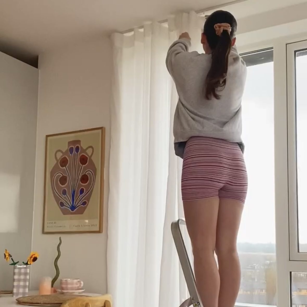 Image of person hanging up curtains.